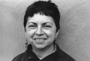 Retrato de Gloria, mujer de cabello corto con aretes, sonriendo